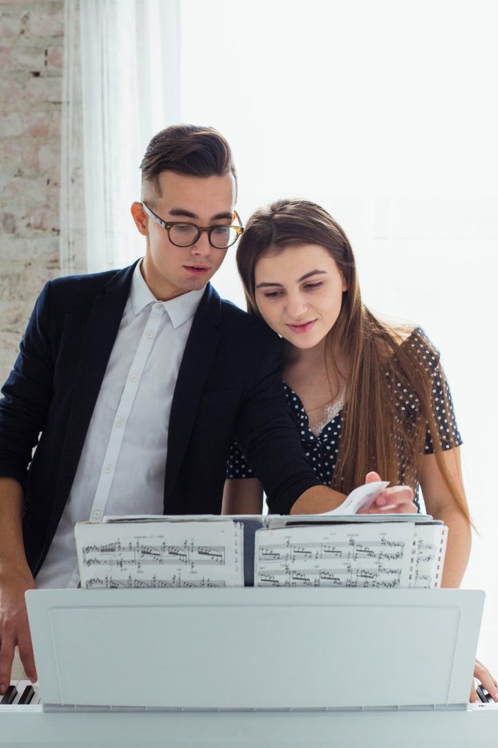 portrait-of-young-couple-looking-at-musical-sheet-learning-to-play-the-piano El reto de estudiar canto a distancia